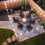 Six dark wooden Adirondack chairs arranged around a glowing fire pit on a gravel patio.