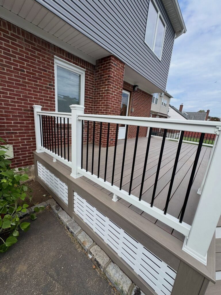 A residential deck with white railings and white lattice skirting panels along the base.