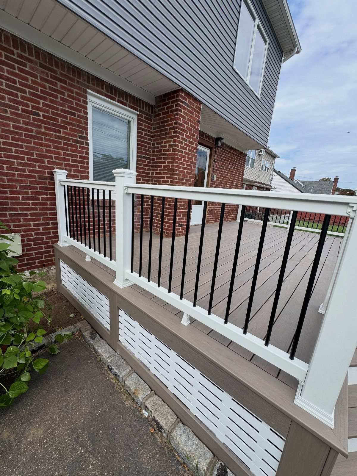 A residential deck with white railings and white lattice skirting panels along the base.