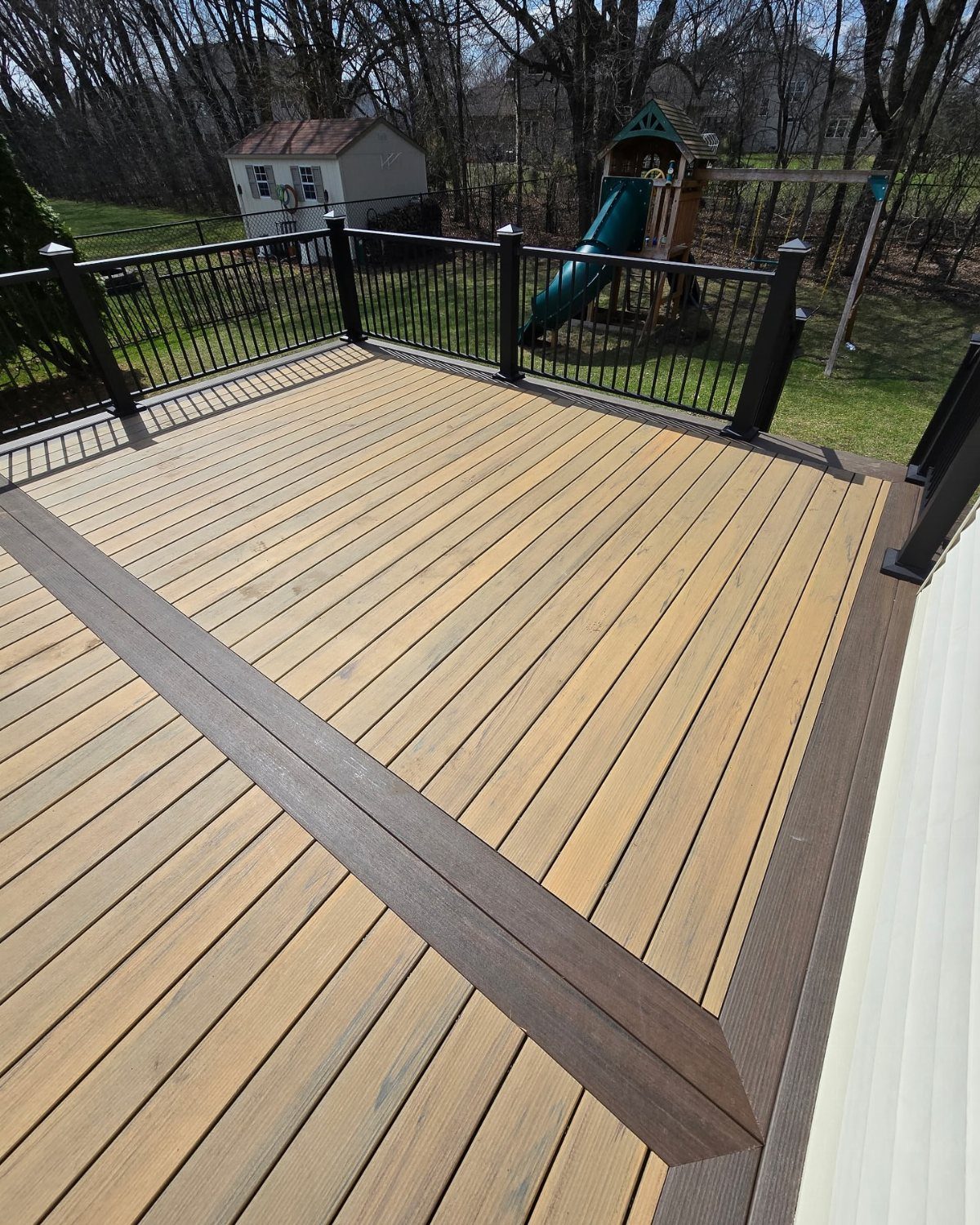 Wooden deck with light tan planks and a dark brown picture frame border design.