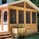 A wooden screened-in porch with large mesh windows and steps leading up to the deck.