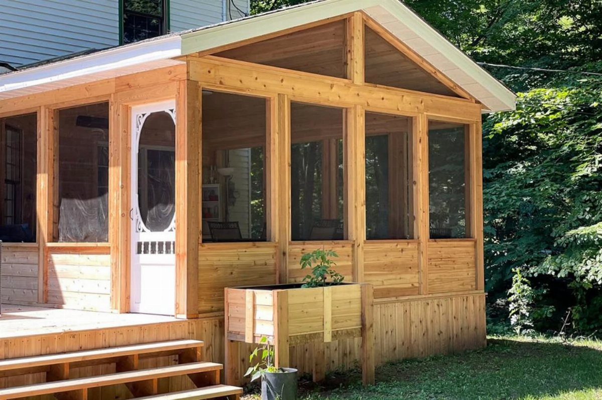 A wooden screened-in porch with large mesh windows and steps leading up to the deck.